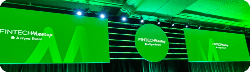 Fintech Meetup conference stage with green branded screens and lighting at a Hyve Event
