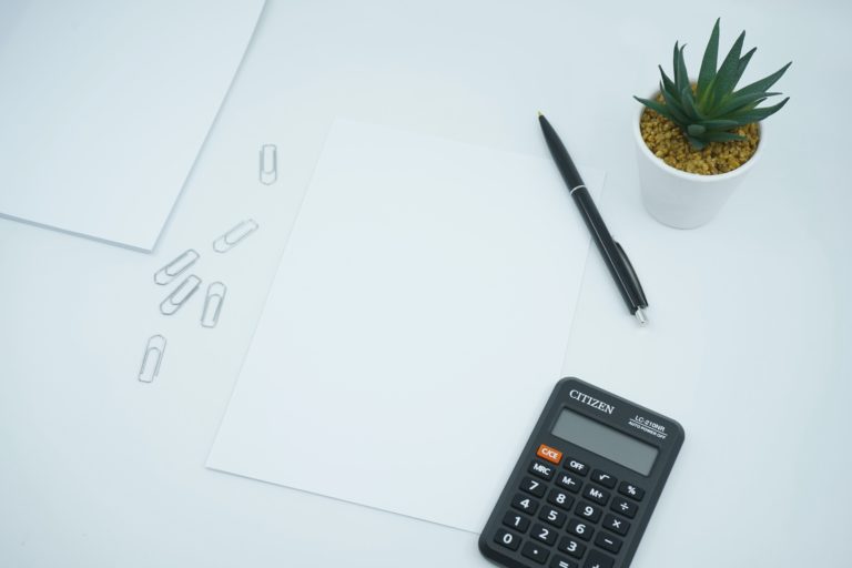 Image of a desk table with a calculator and pen