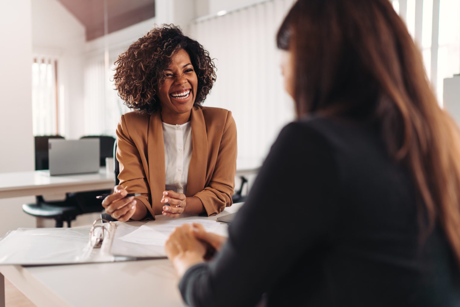 Image of two people talking to each other over a desk