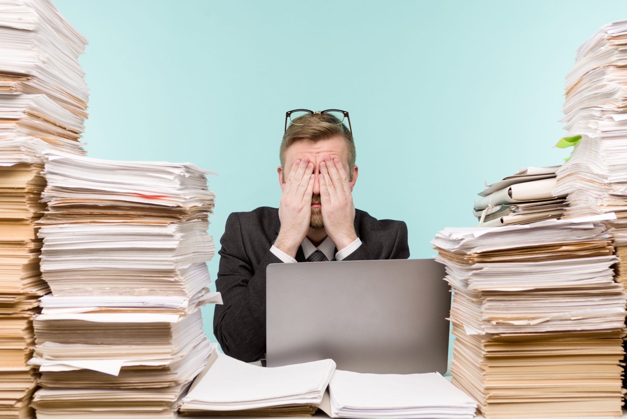 Image of an overhelmed man surrounded by papers